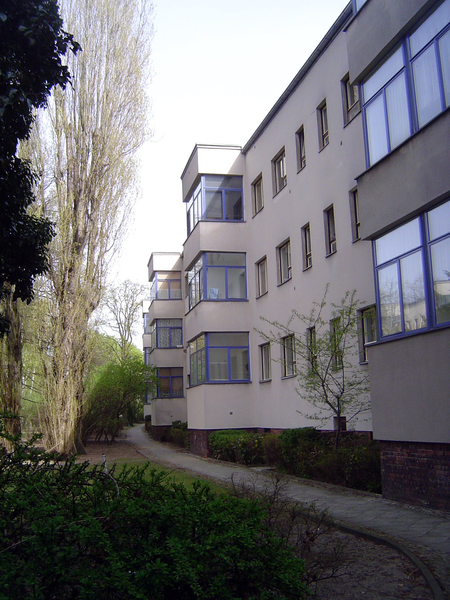 The back of the curved buildings opens on greenspace with glassed-in balconies.