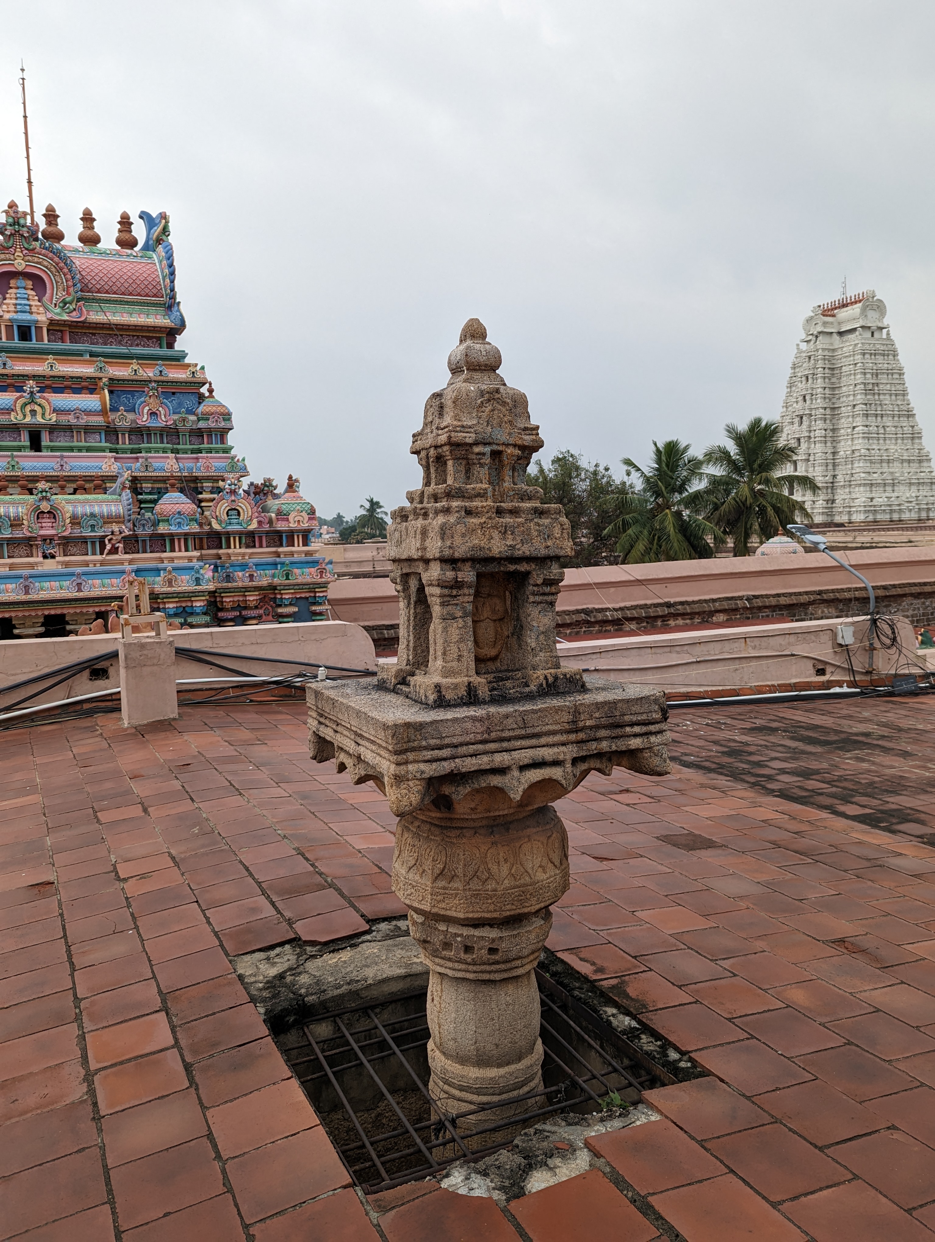 A dhvajastambha or flagstaff sticks through a recently built roof over the main axis.  On a scale of 1 to 10, the craftsmanship of the templ