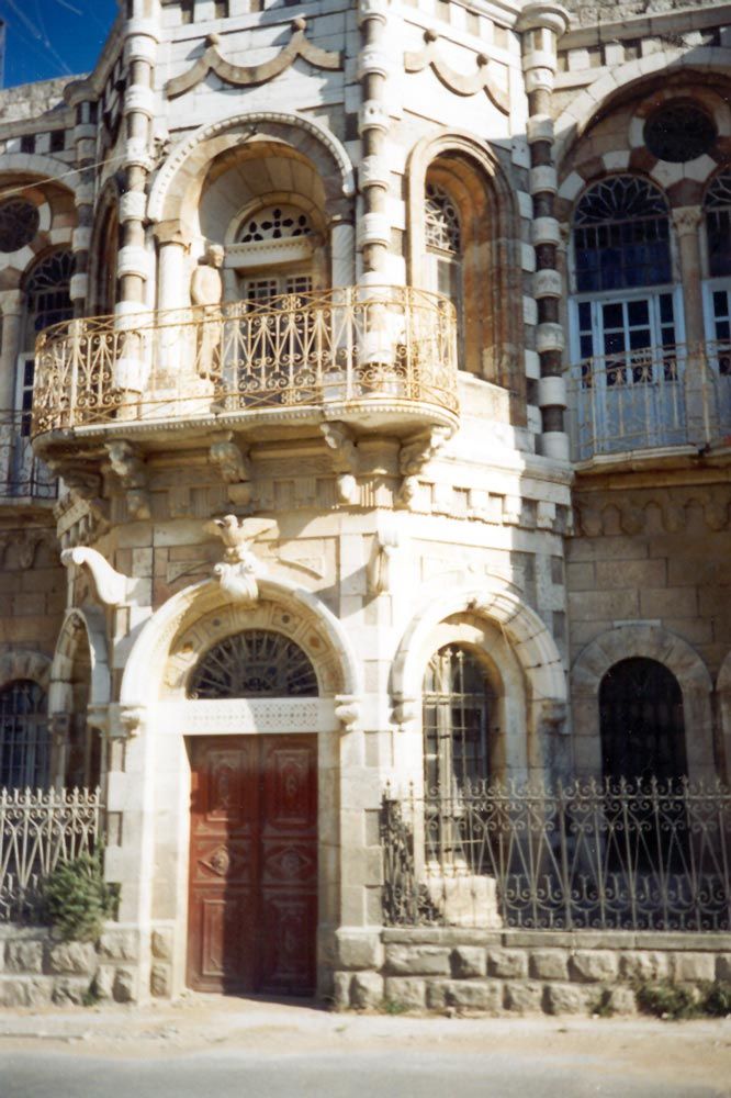 Close-up of the entrance to the same building. A life-sized statue of one of the builders of the house can be seen standing on the balcony.