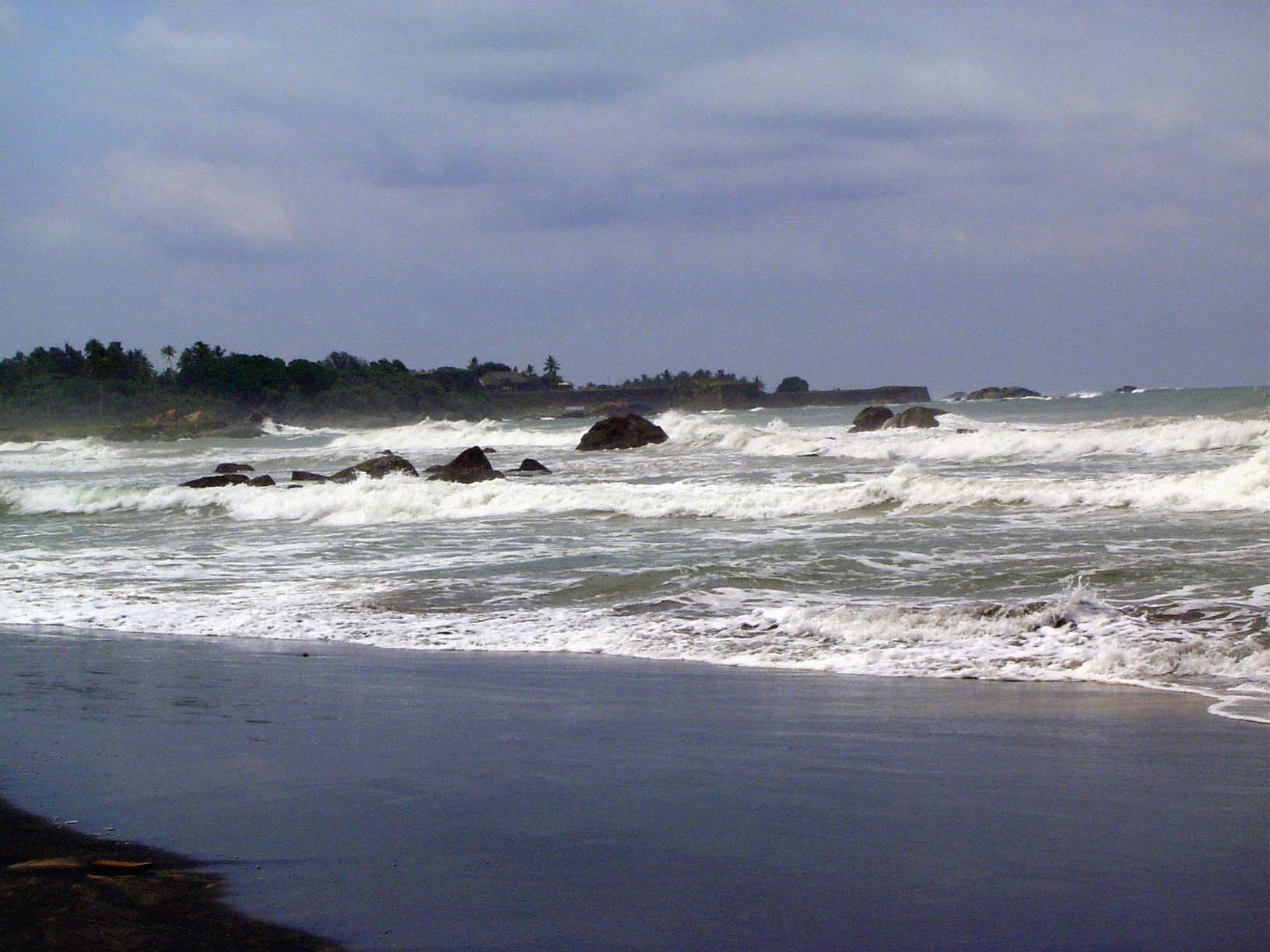 We're looking past the rough surf toward the rocky and roughly square fortress of historic Galle, which sticks out into the Indian Ocean lik