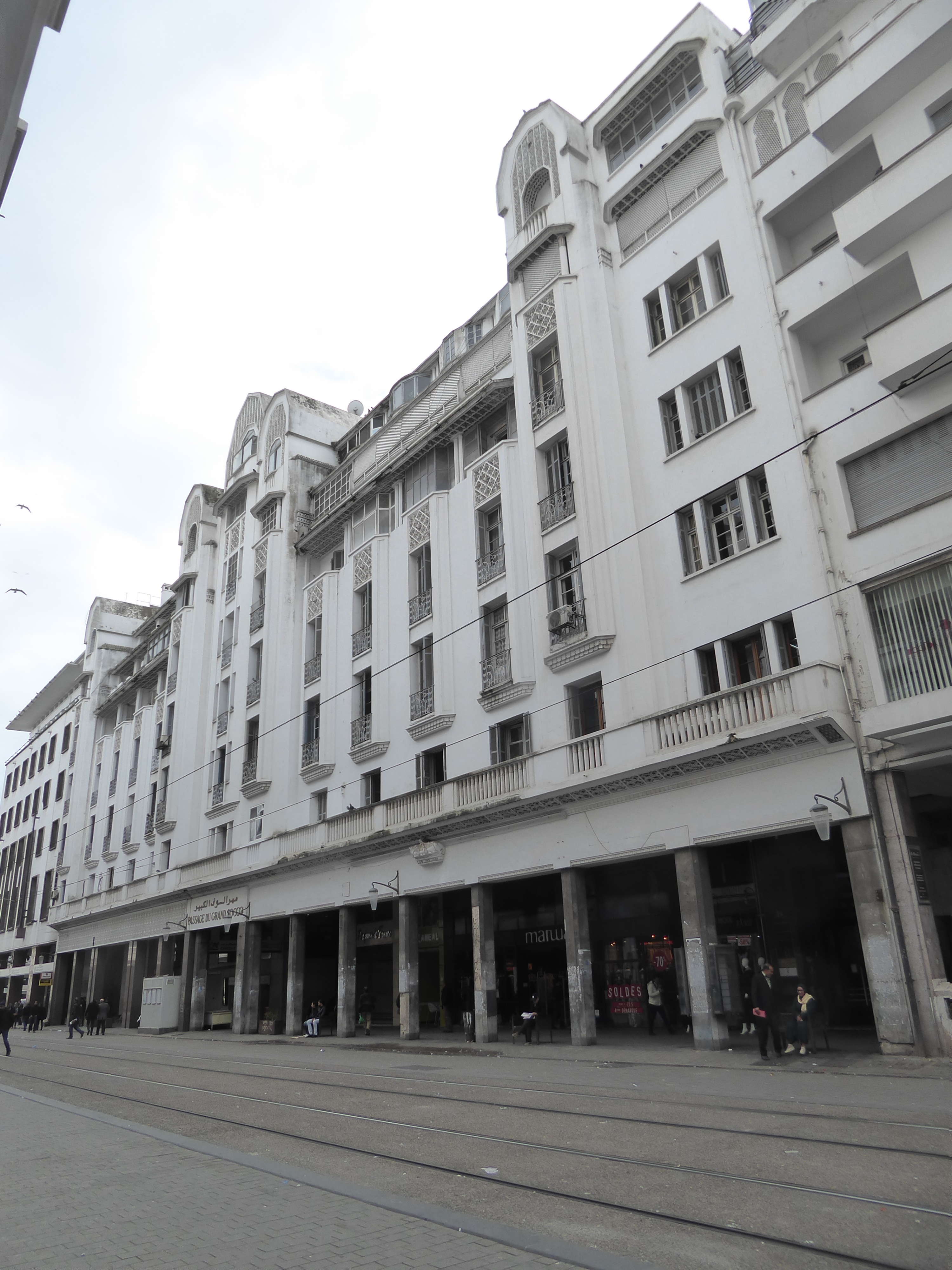 Buildings lucky enough to face main streets front and back were often designed with cross-cutting arcades lined with shops. Here, barely vis