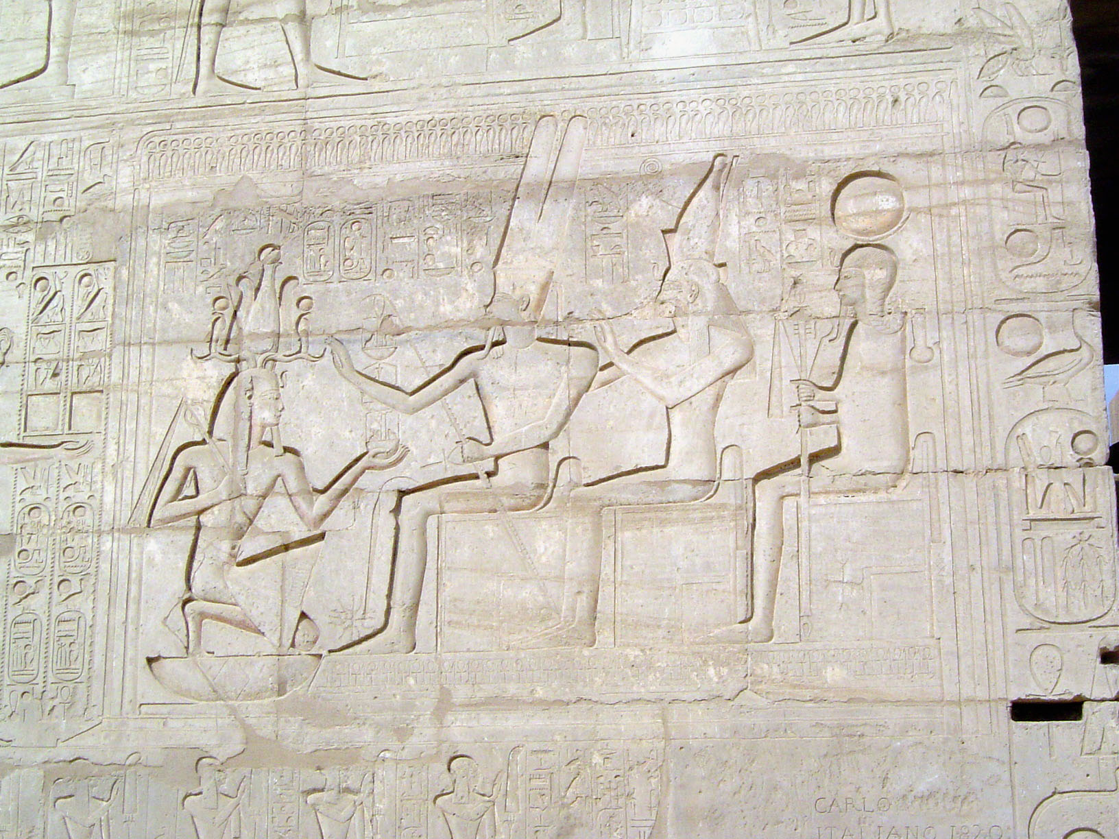 Meanwhile, Rameses II kneels before the Theban triad, Amun-Ra, Mut, and Khonsu.