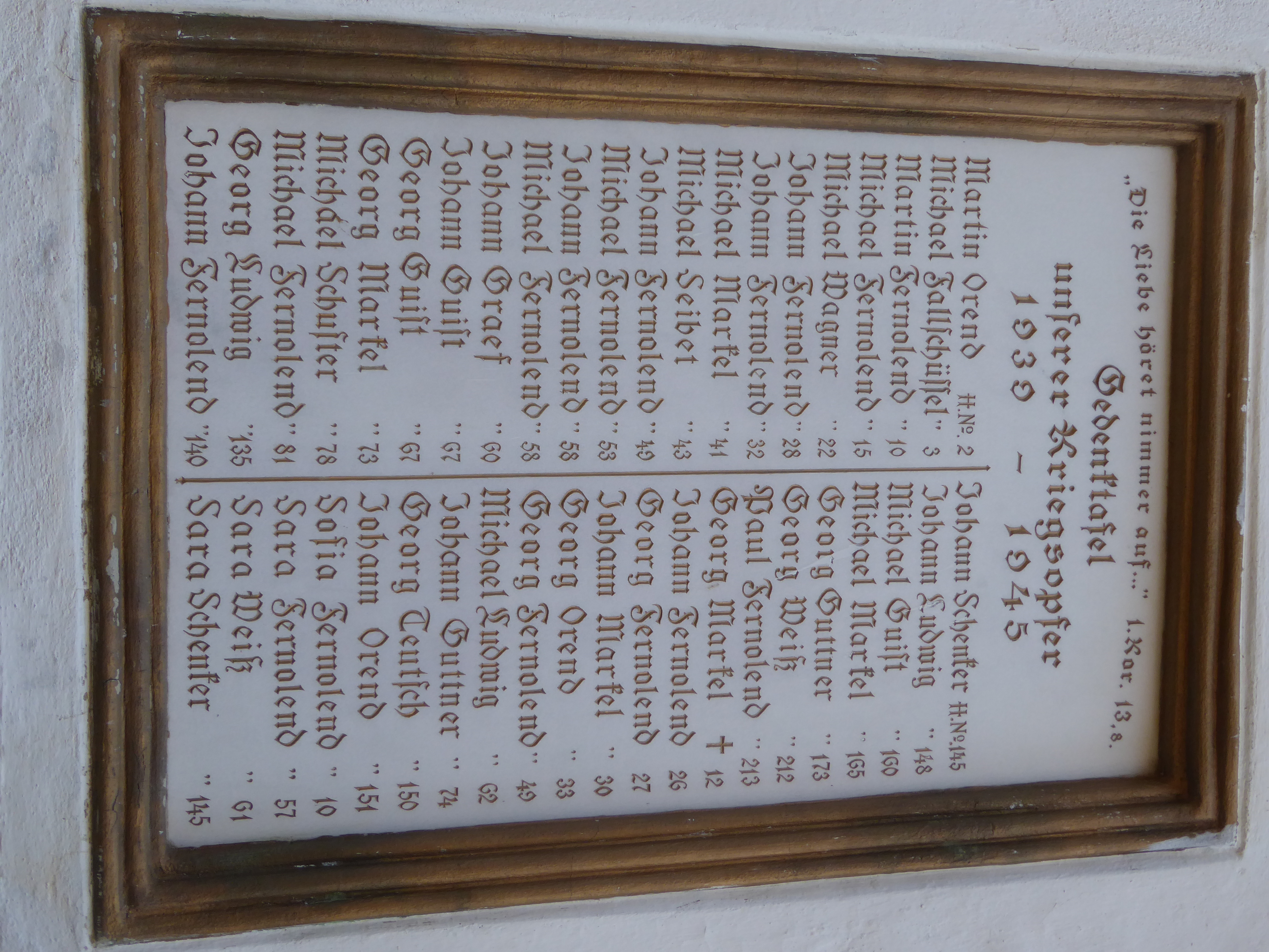 The church wall holds a list of the village's World War II losses. How are they identified? By house number.