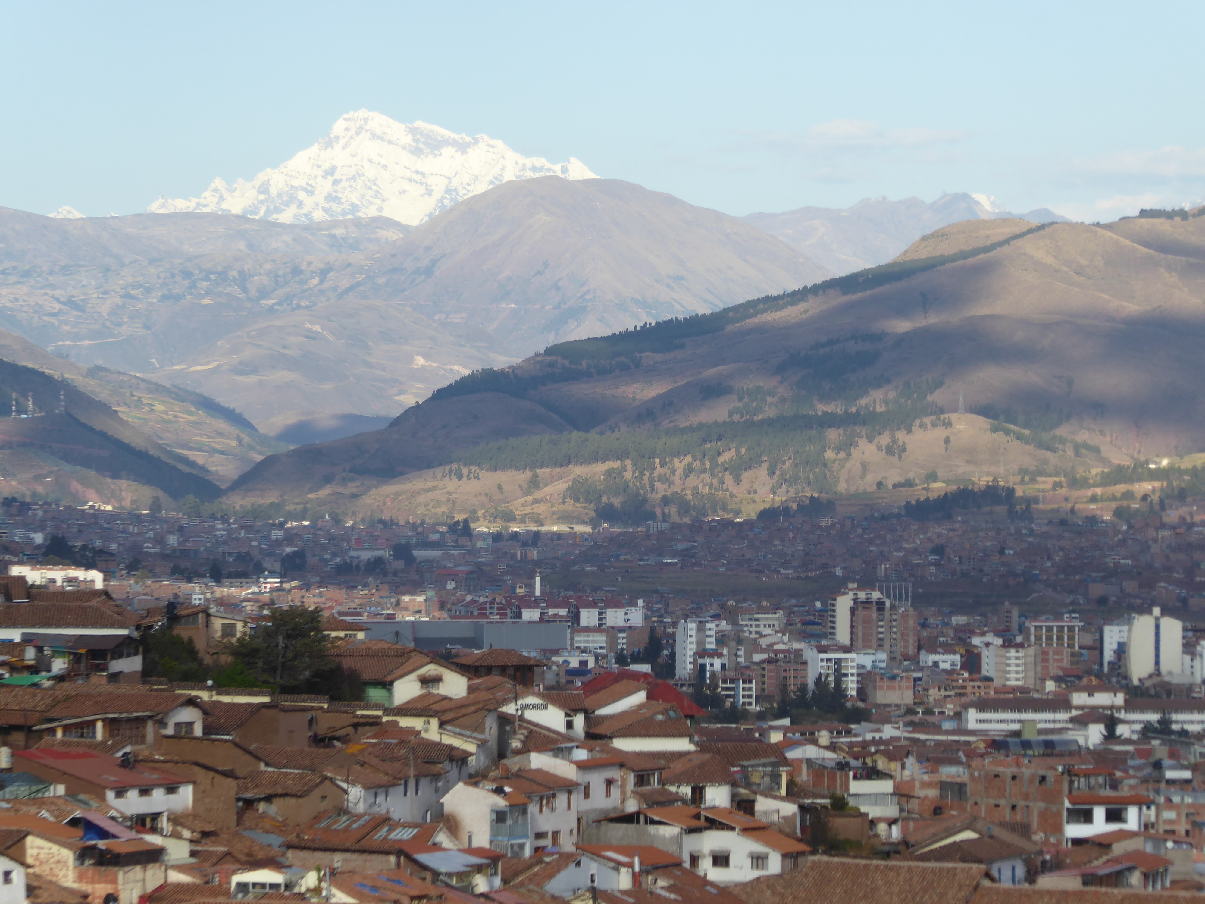 The National Geographic caption would read something like: "The snow-capped peak of Ausangate rises 60 miles beyond thriving Cusco." Here's