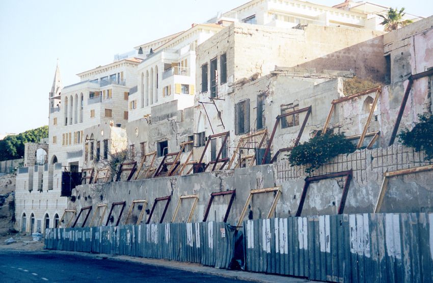 On the edge of collapse, old buildings await their conversion into the facades of new buildings.