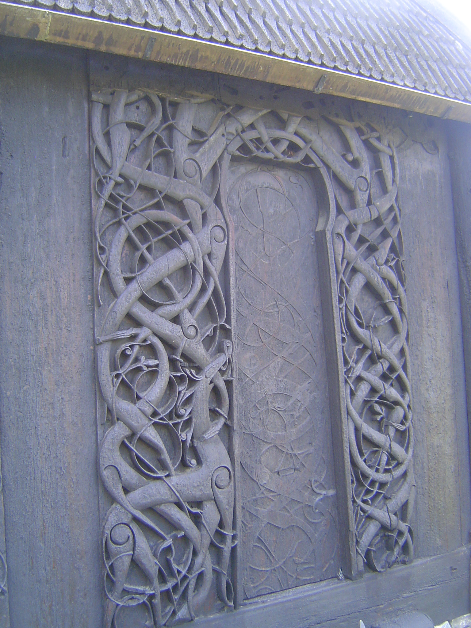 On the north side of the church, there's an old doorway framed by two carved jambs. The image appears to show creatures "Urnes beasts" bitin