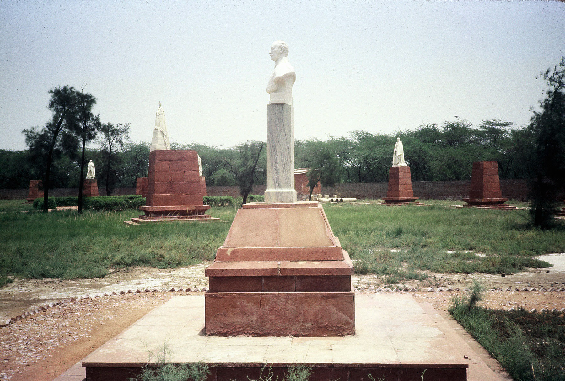 George stands surrounded by acolytes, or in some cases merely their plinths.