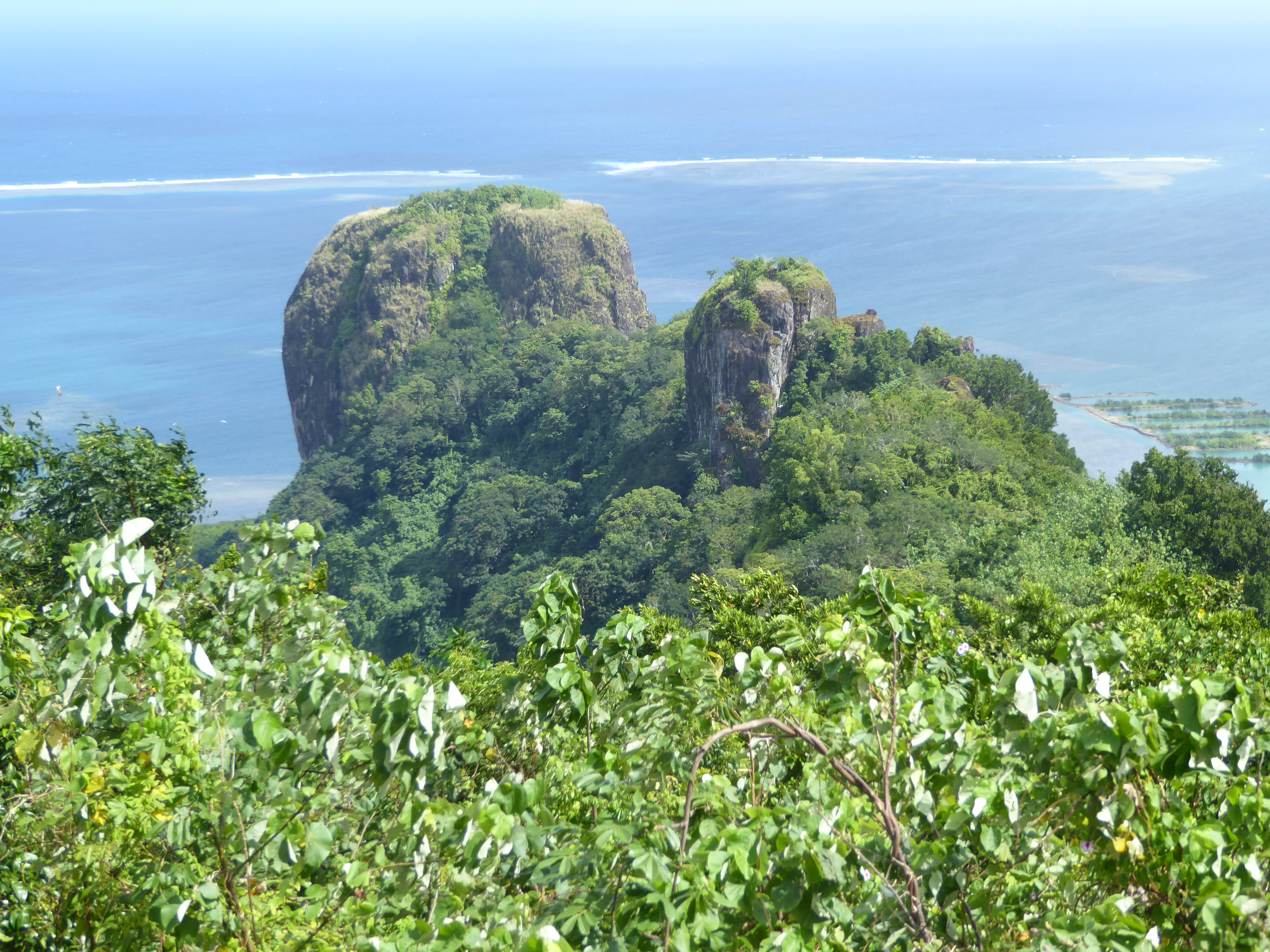 Here's the same rock from the other side. The island's coral-reef necklace is on display, along with two of the several natural breaks in th
