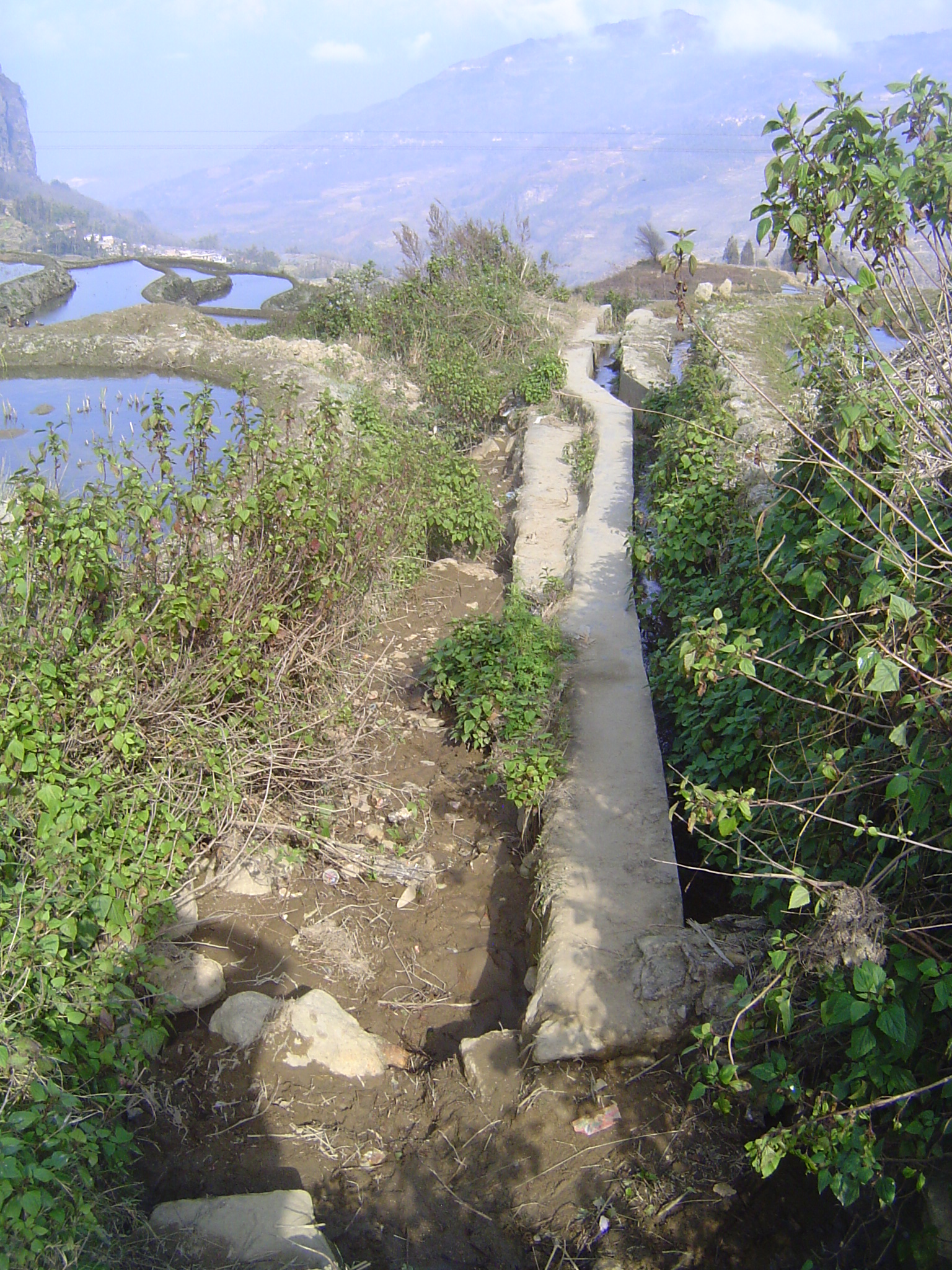A forking concrete channel takes off to the right, while the main channel drops into a gulley.