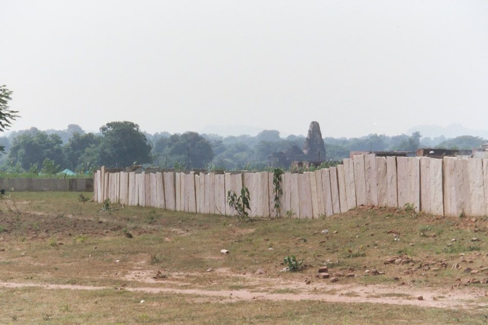 Bedrock provides material for the occasional fence. The background temple is Duladeo, a late Khajuraho temple. Khajuraho is located near the