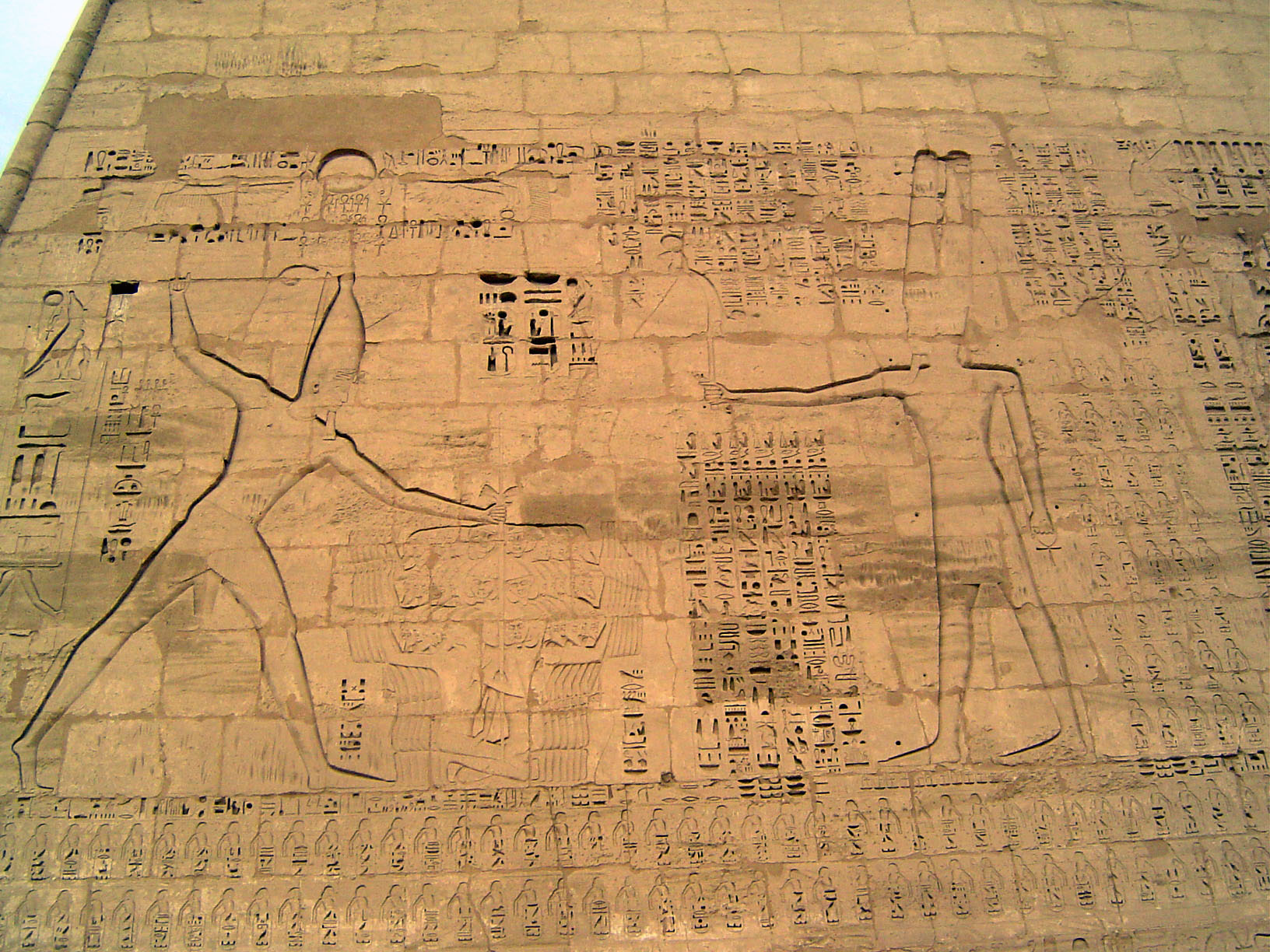 On the face of the first pylon is this image of Ramesses III holding his enemies by the head and offering them to Amun, who holds a short sw