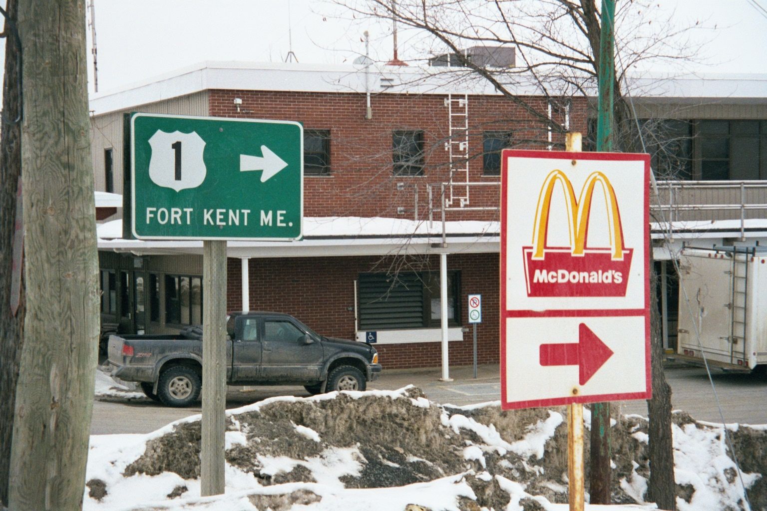 A few miles north, at Clair, New Brunswick, the green sign points to the international bridge crossing to Fort Kent. The McDonald's sign poi