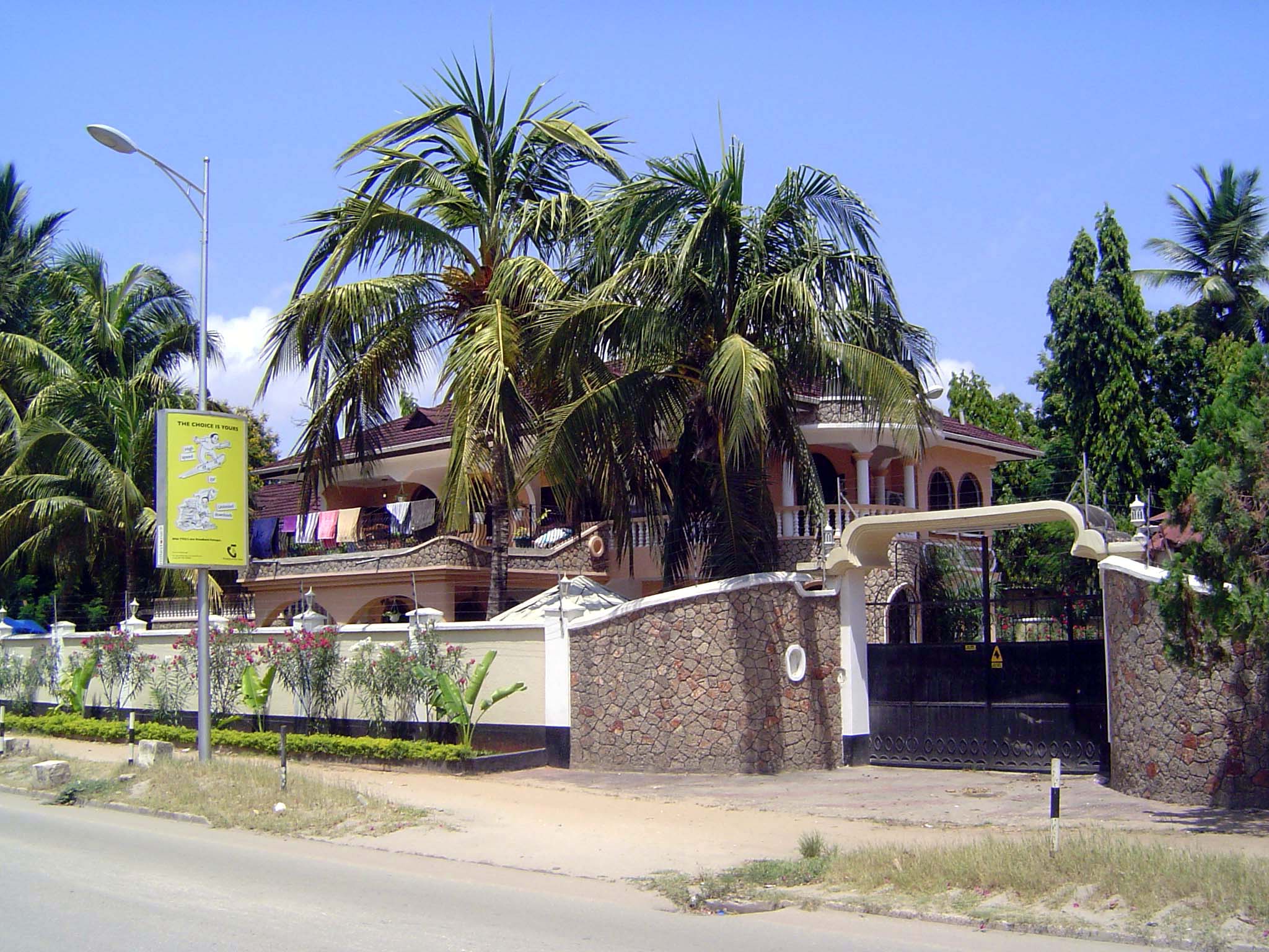 Some single-family homes survive in Upanga. Here's one, a bit of a puzzle. Clothes hung out to dry in a mansion? Note the electric fencing a