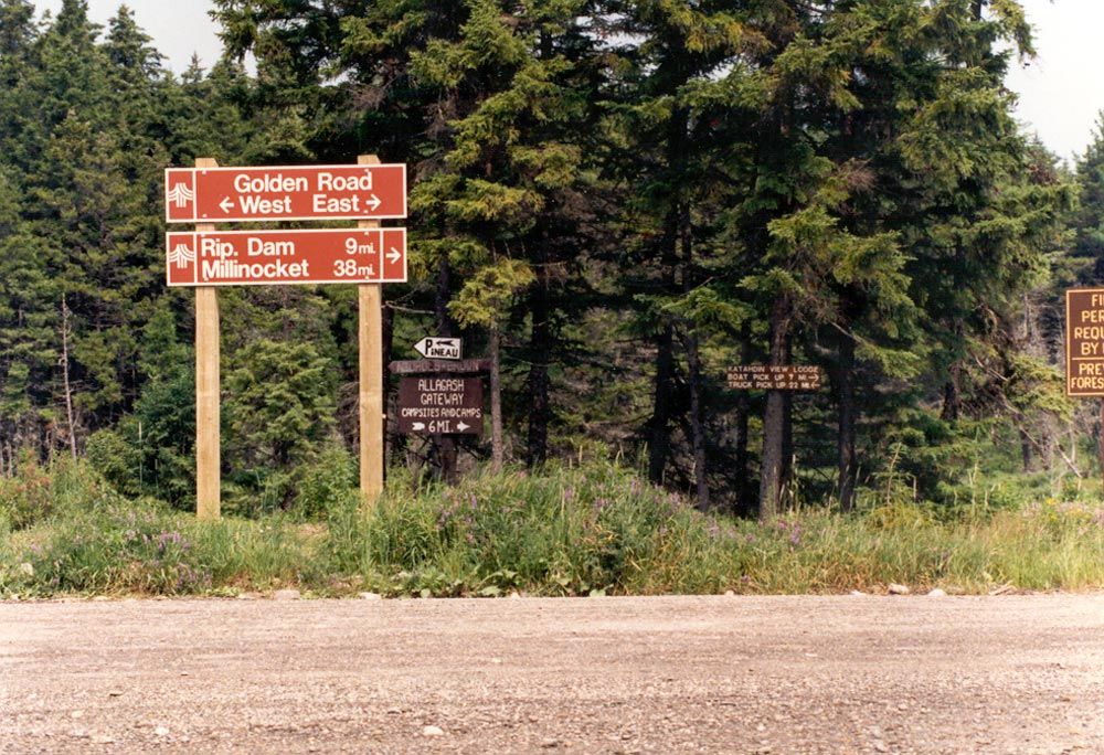 The roads through this part of Maine are private, though the landowners permit controlled public access. The stylish red signs here are on t