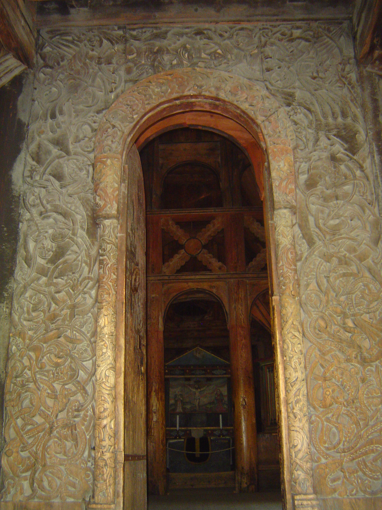 The jambs, lintel, and the columns supporting the curve of the archivolt are covered with carved vegetation and near the top of the opening