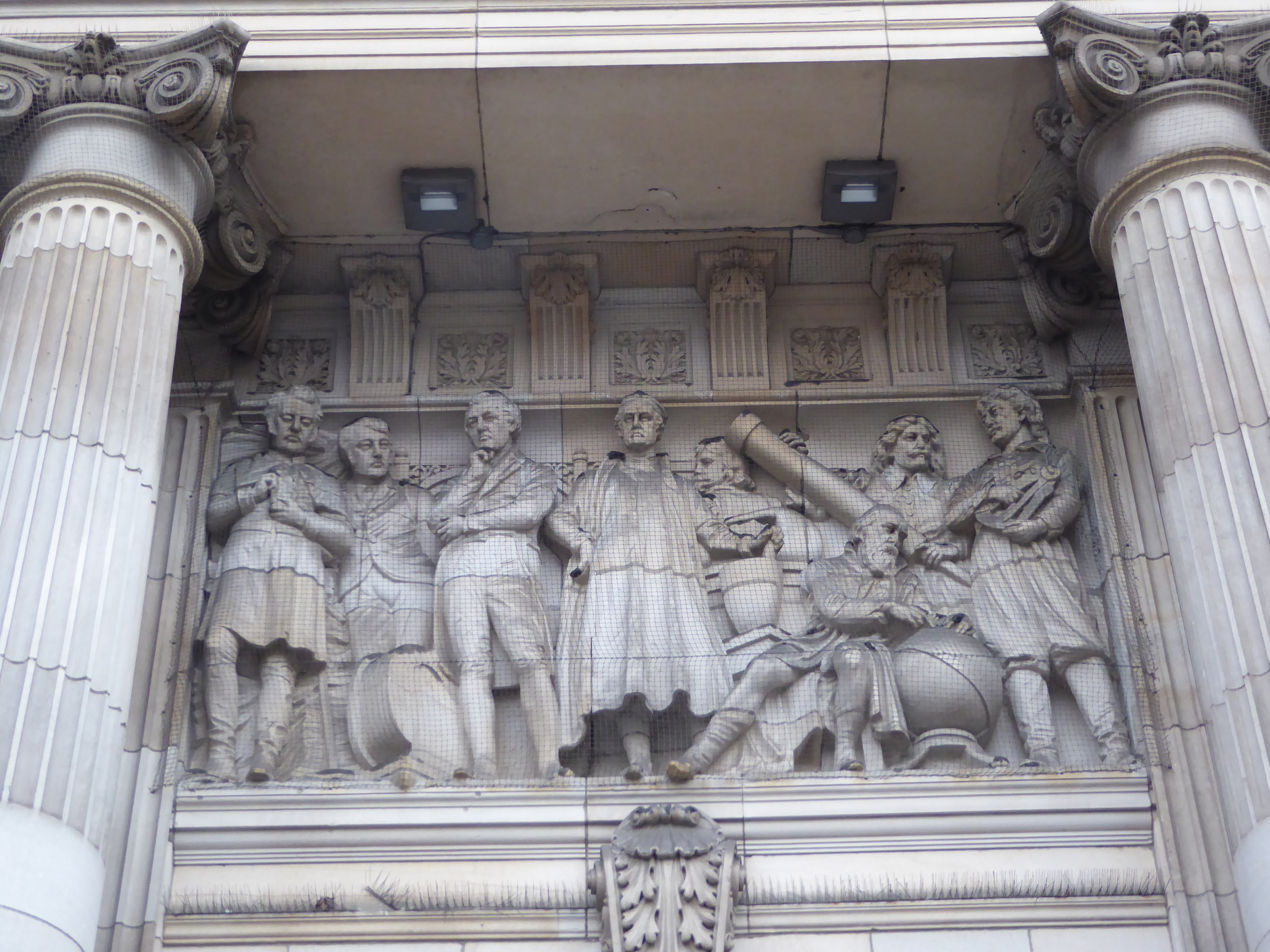 Panels over the entrance represent Art, Science, and Commerce. Presumably this is science, though the question of the moment seems to be "Wh