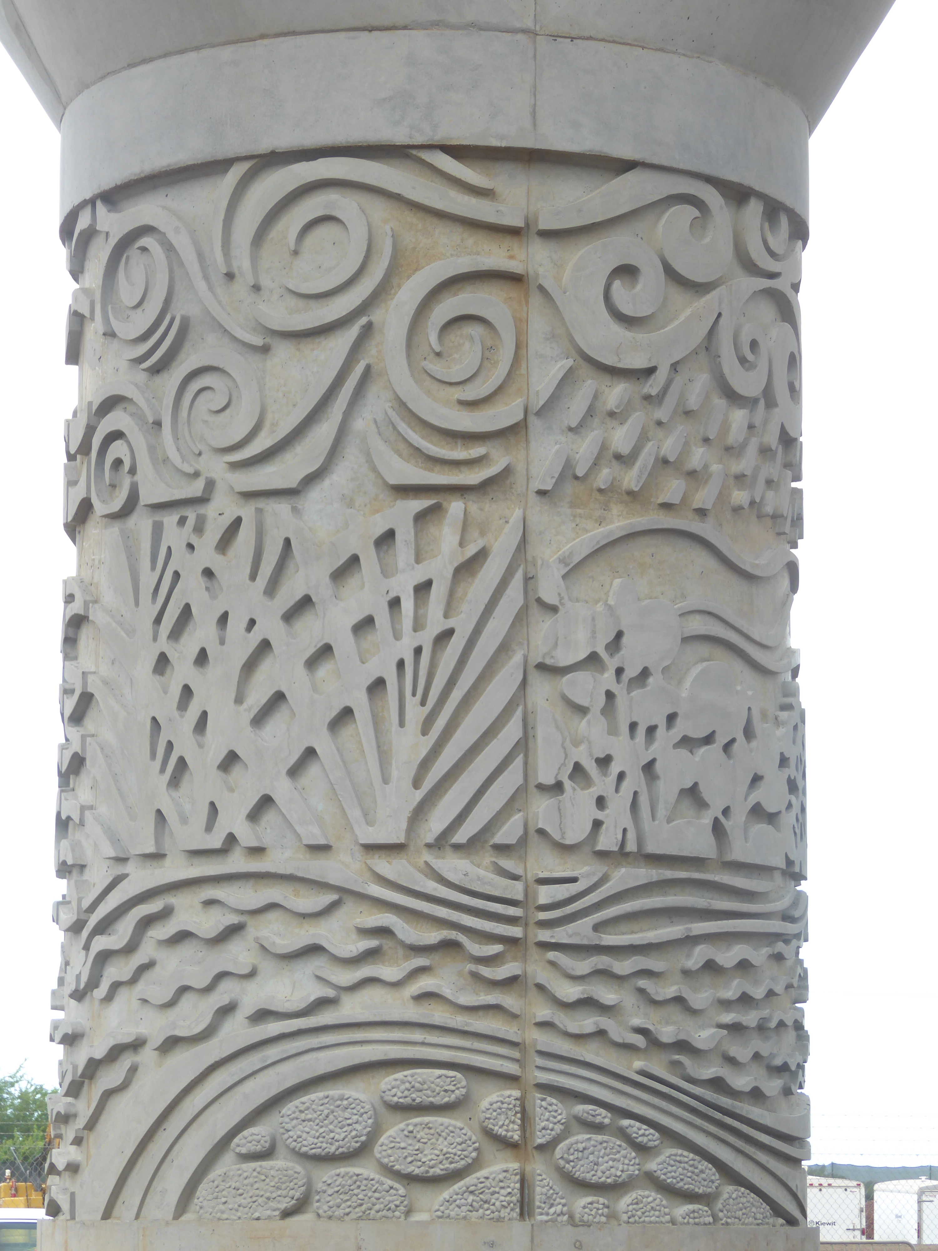 Some of the posts carry symbols of wind, rain, sun, coral, salt beds, and the ulu or breadfruit tree. The design is by Daniel Kanekuni from