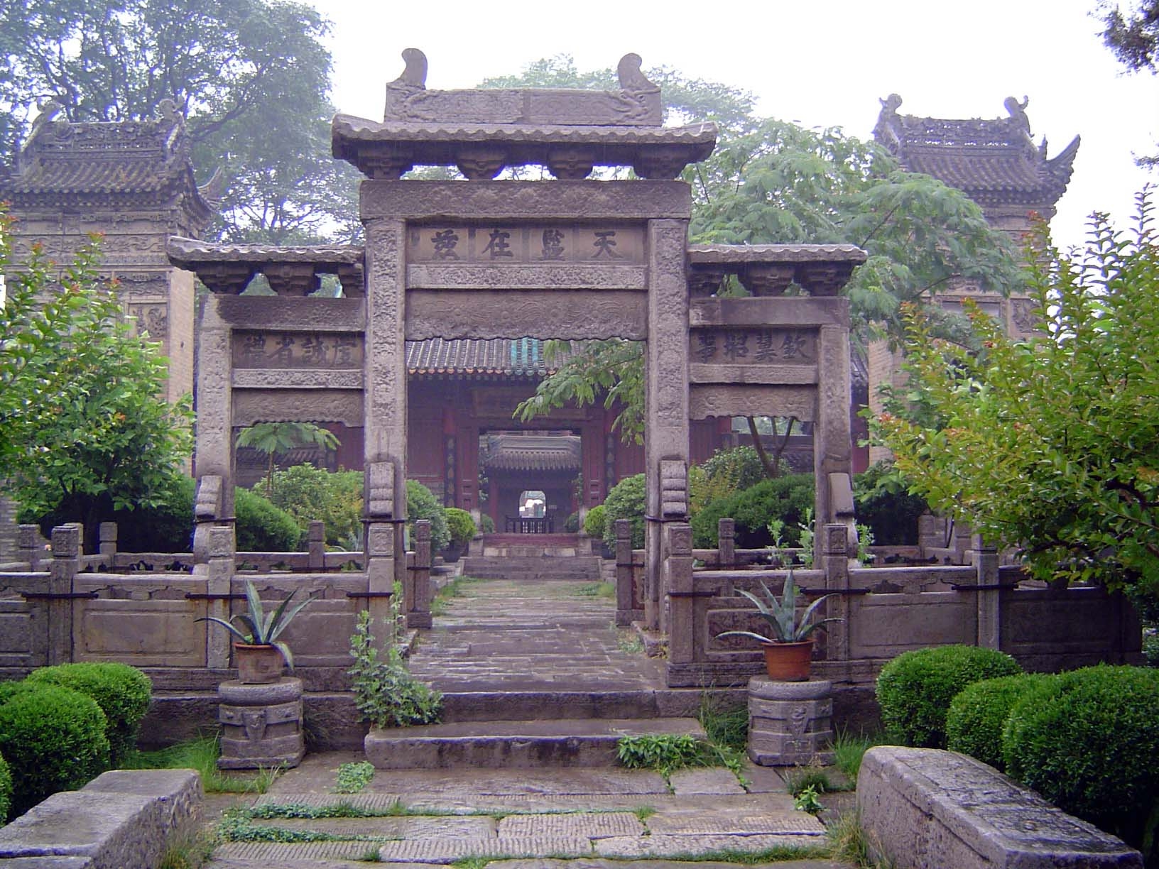 Stone gateway with tablet pavilions rising behind it on either side.