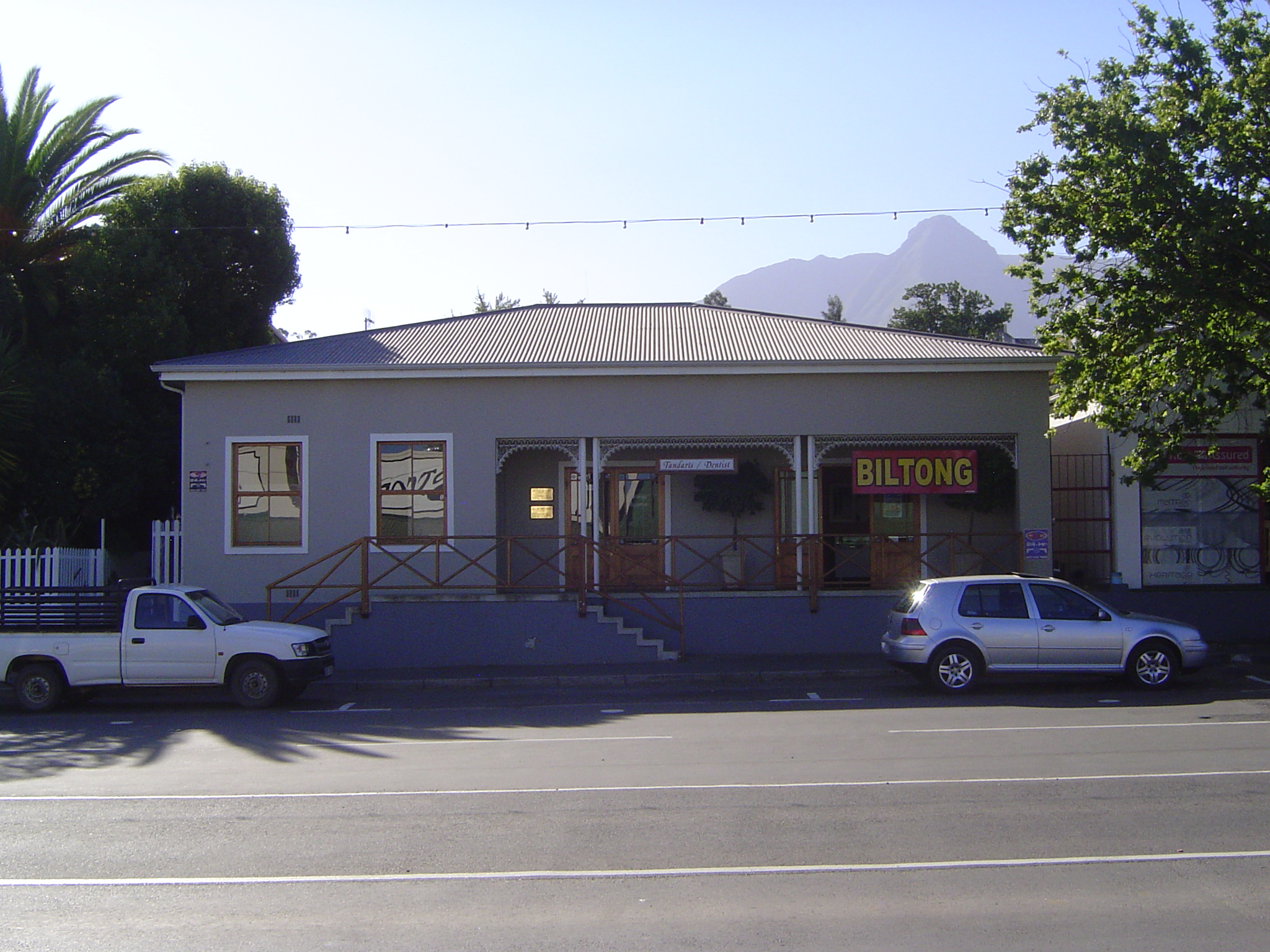 A house once, the gable was removed and the building divided into two businesses: dentist on the left, biltong shop on the right. The stuff