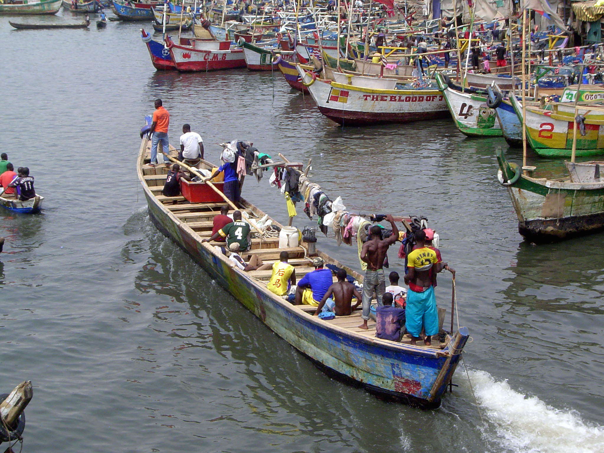 A boat returns, with laundry hung over a long beam.
