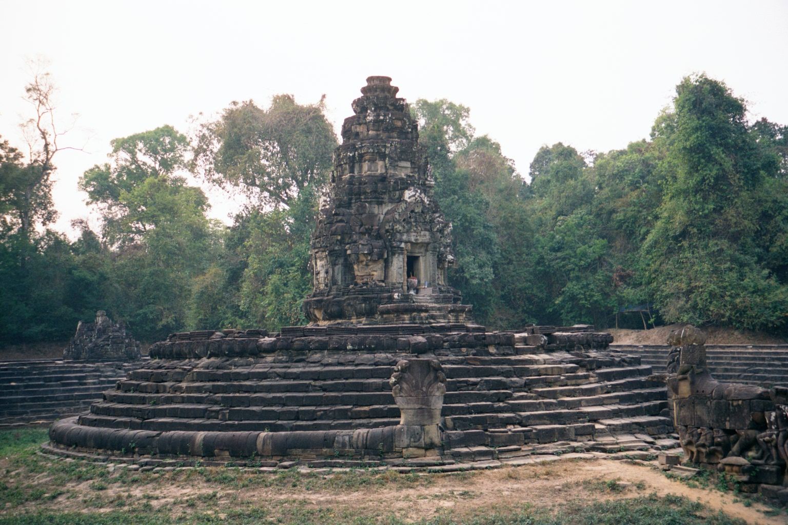 The ensemble is Neak Pean, "entwined serpents." The flaring hood of one of the seven-headed serpents is straight ahead. Its body coils aroun