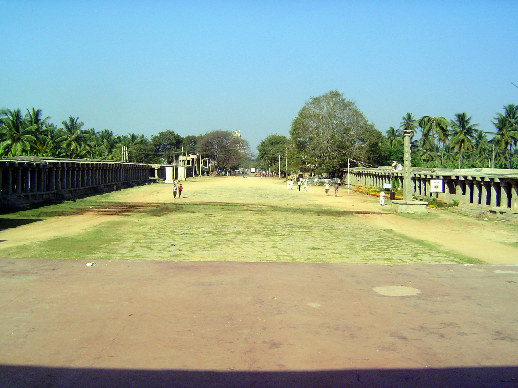 The view in the opposite direction, with the east gopura of Virupaksha peeking over a tree. Some accounts suggest that the width of the stre