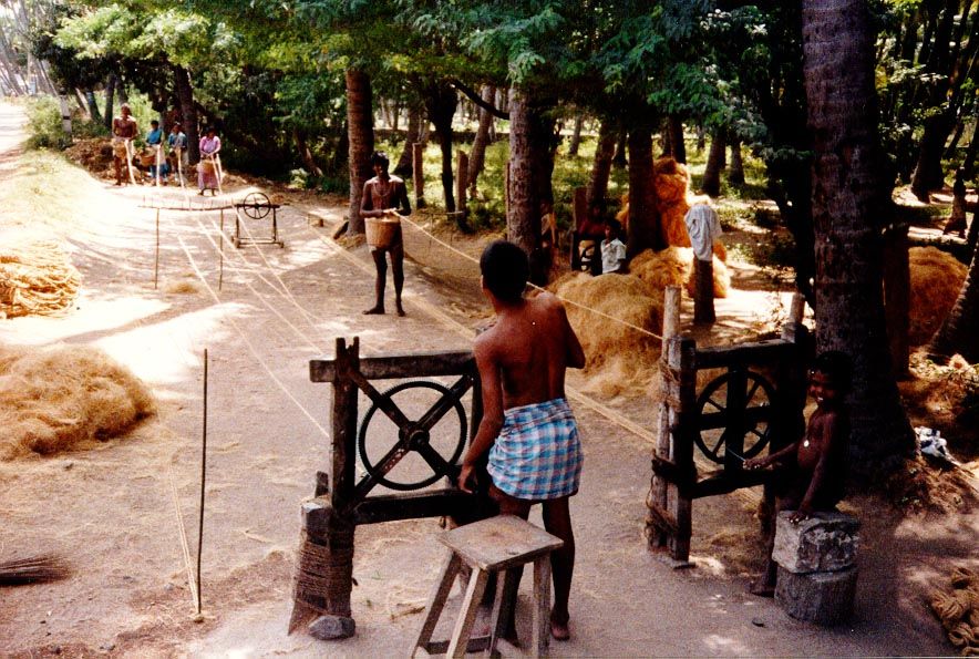 A British introduction? Probably. A rope-making machine in Tamil Nadu twists coconut fiber into rope; the women in the background feed mater