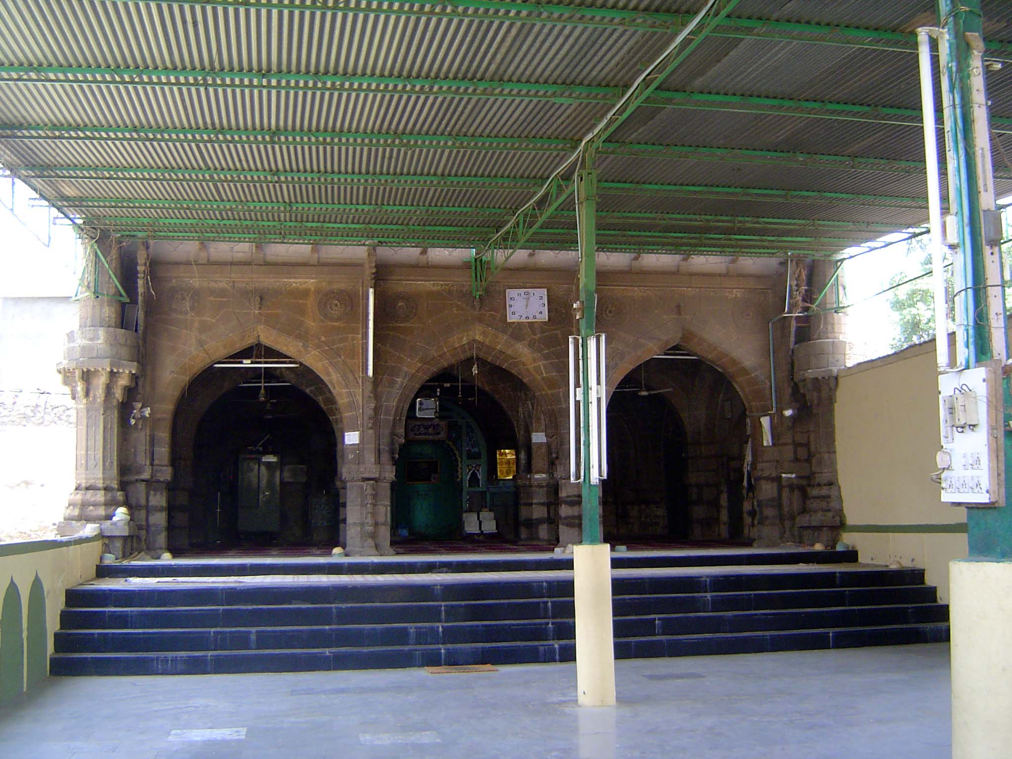 The mosque behind the gate has always been small, but it has lately been greatly improved with corrugated sheetmetal roofing, fluorescent tu