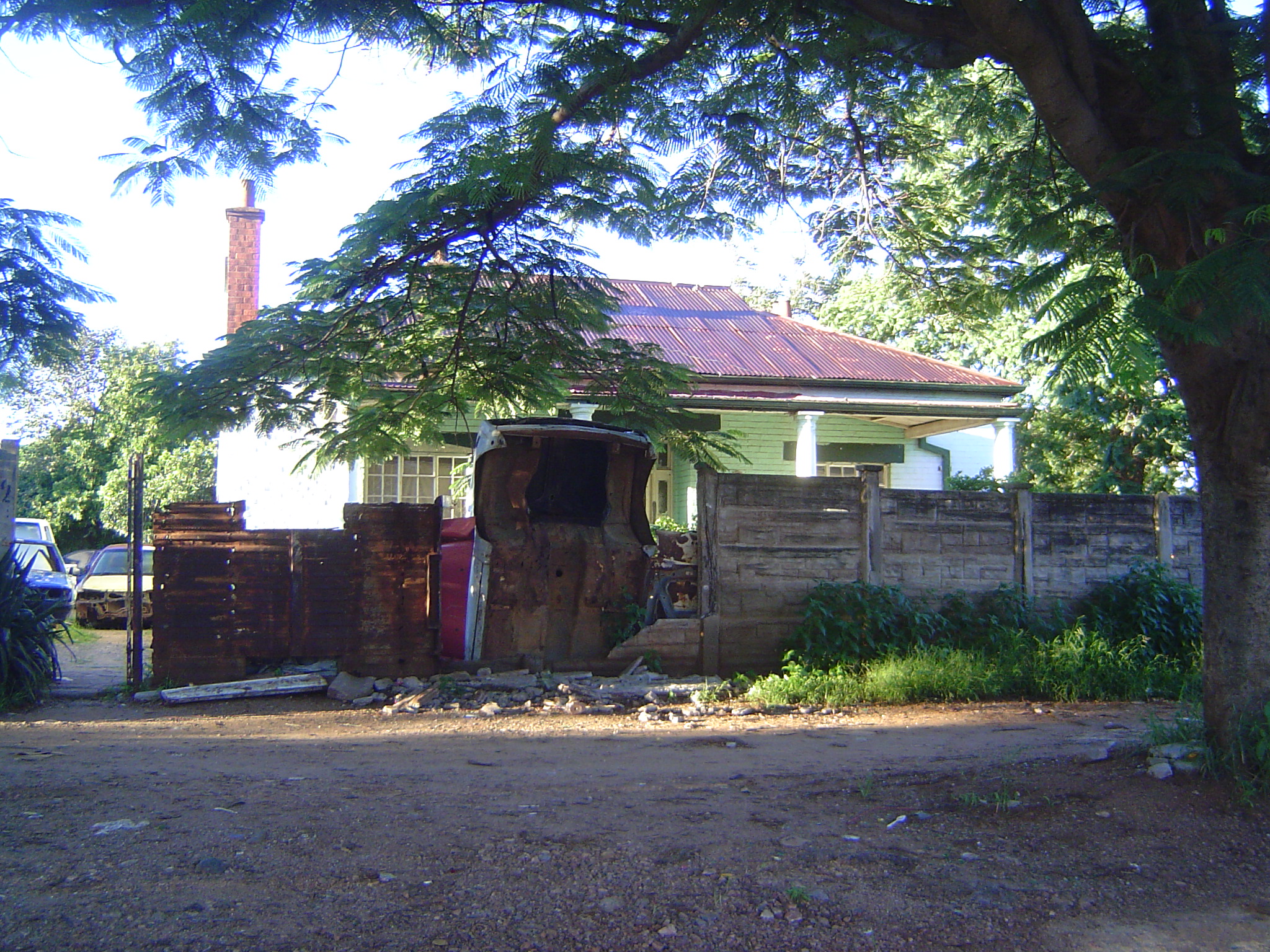 Here's a house at the edge of City Centre, in a rundown neighborhood where fences are made of whatever's available. The owner is getting by