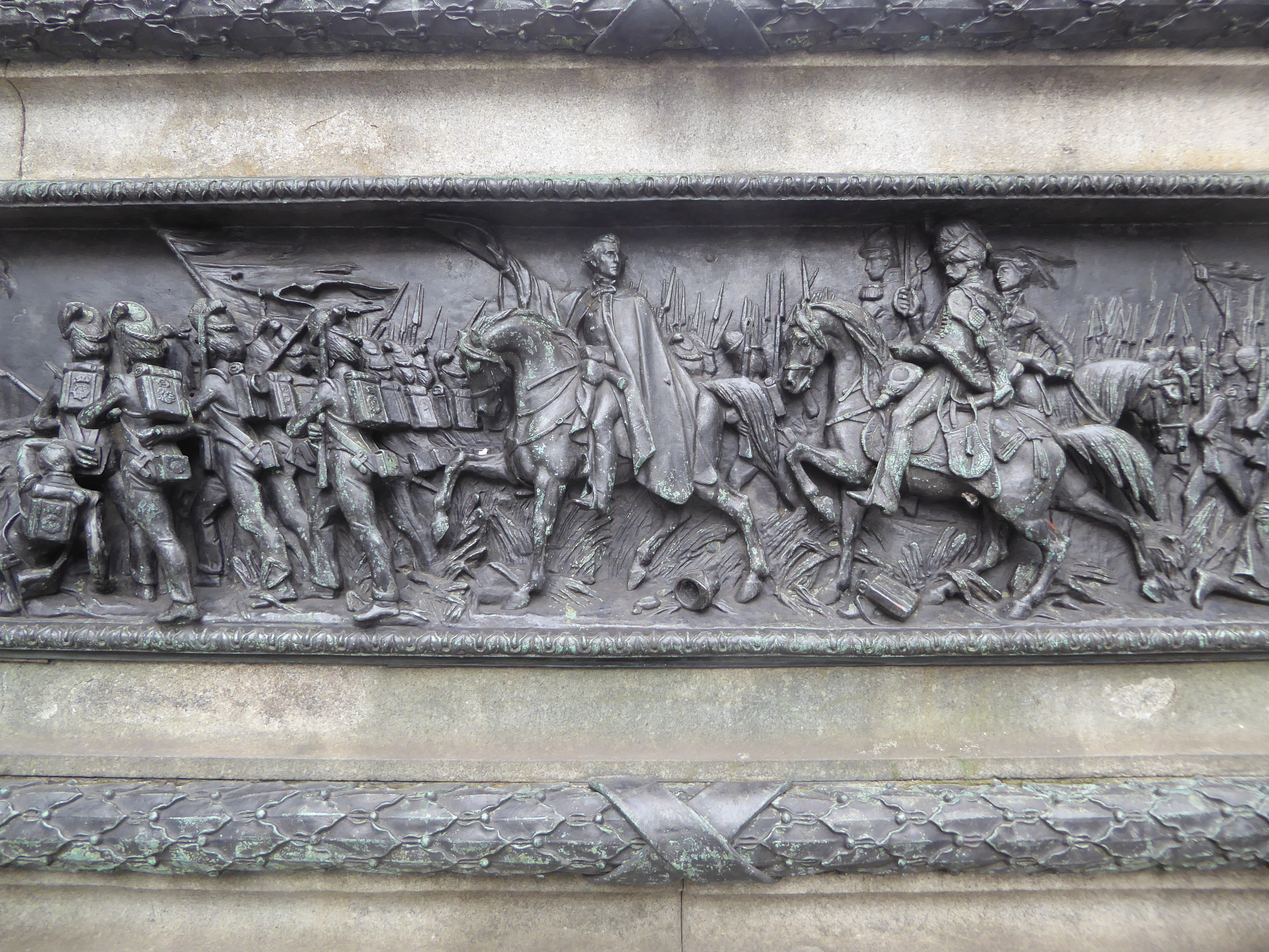 The base of the statue has a bronze version of the Battle of Waterloo.