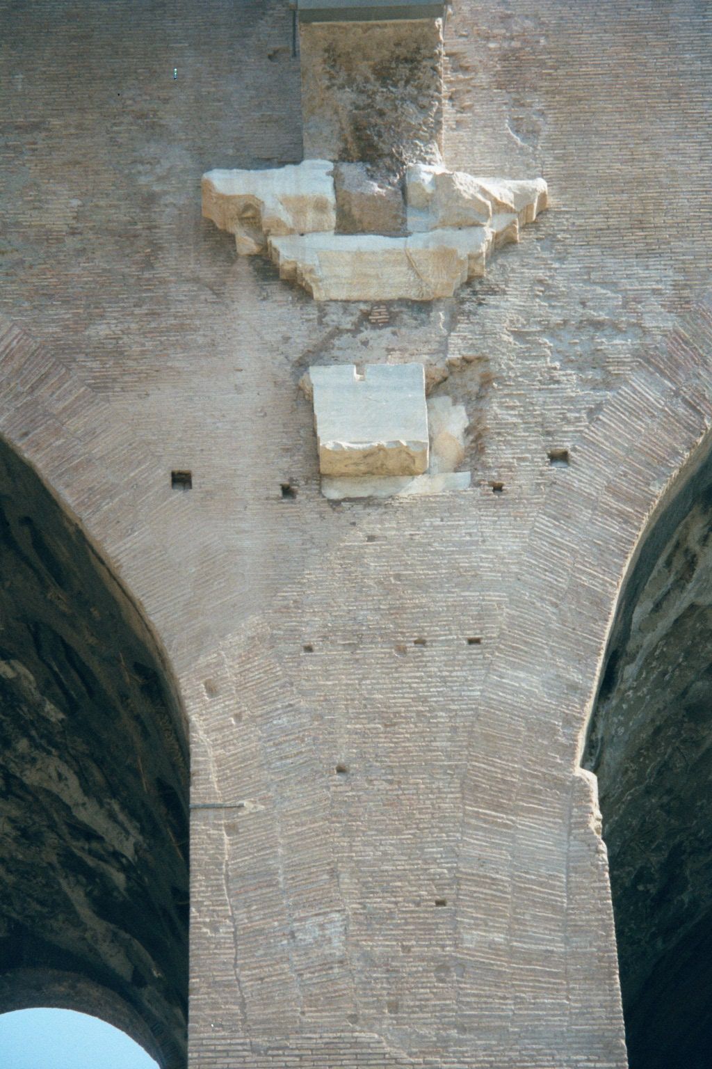 The building was originally sheathed in marble and, higher up, stucco; only brick and concrete survive, along with the stone springing of ar