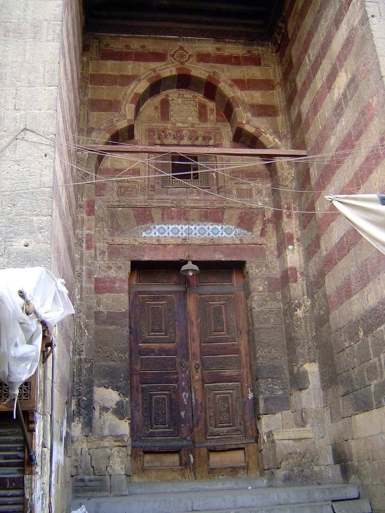 No. 109. The Mosque of al-Fakahani, with trilobate entrance with ablaq decoration. Inside, there's a covered courtyard, but the whole place