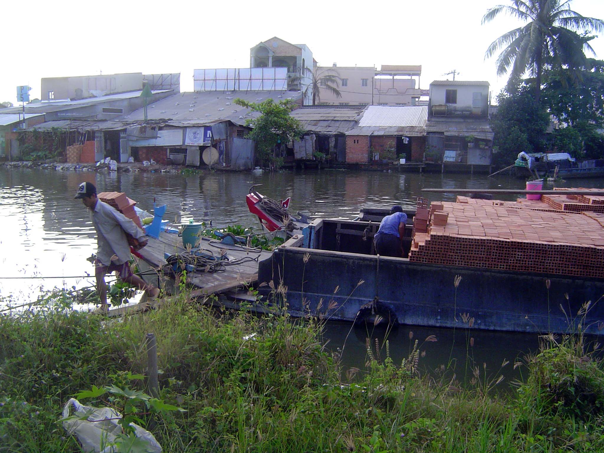 A barge loaded with brick is unloaded the hard way.