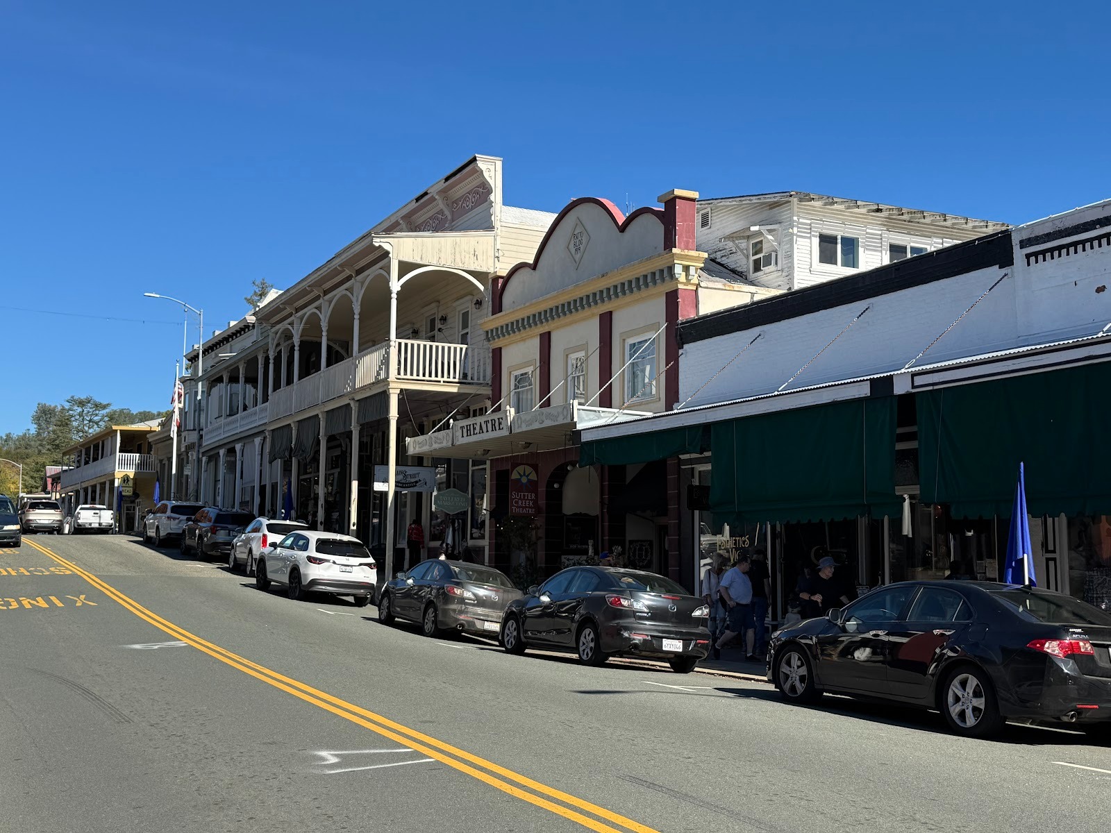 Across the street, the building with the balcony sells women's clothing and in 2025 was partly for rent.  One building closer is the town's